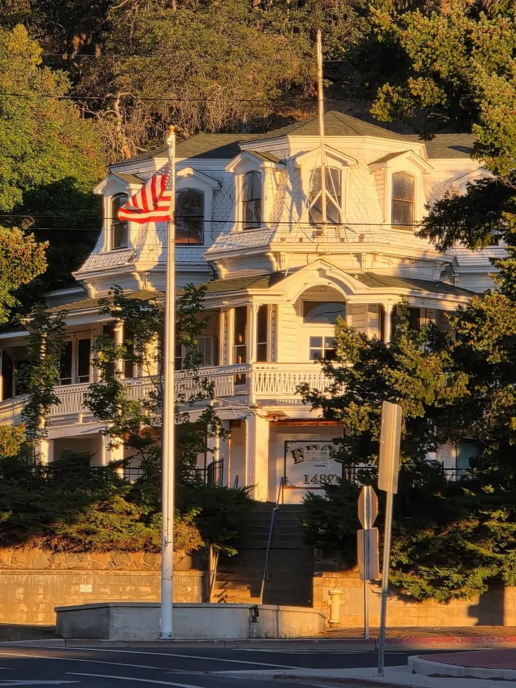 Historic white Victorian house with an American flag at golden hour in Susanville
